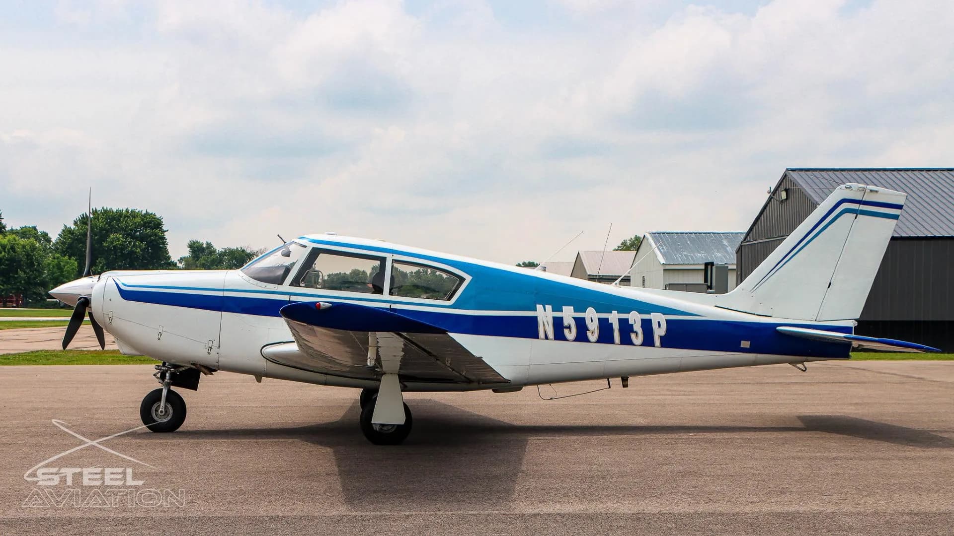 A side view of the white and blue single-engine aircraft N5913P parked on a tarmac.