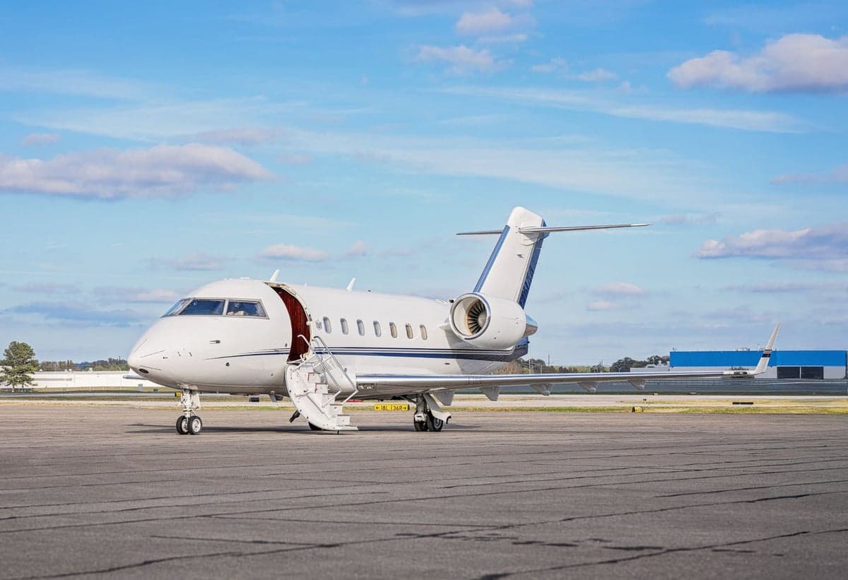 A Challenger aircraft is parked on the tarmac with the stairs down.