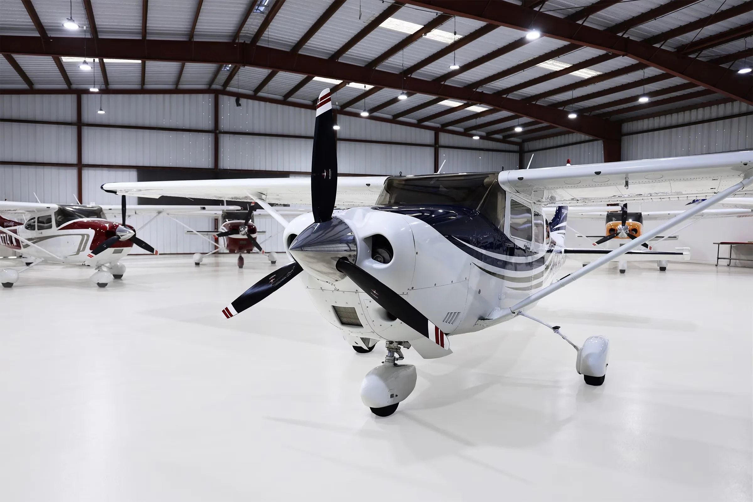 A close-up front view of a white and blue Cessna 206 Stationair TC aircraft with tail number N583ED in a hangar.