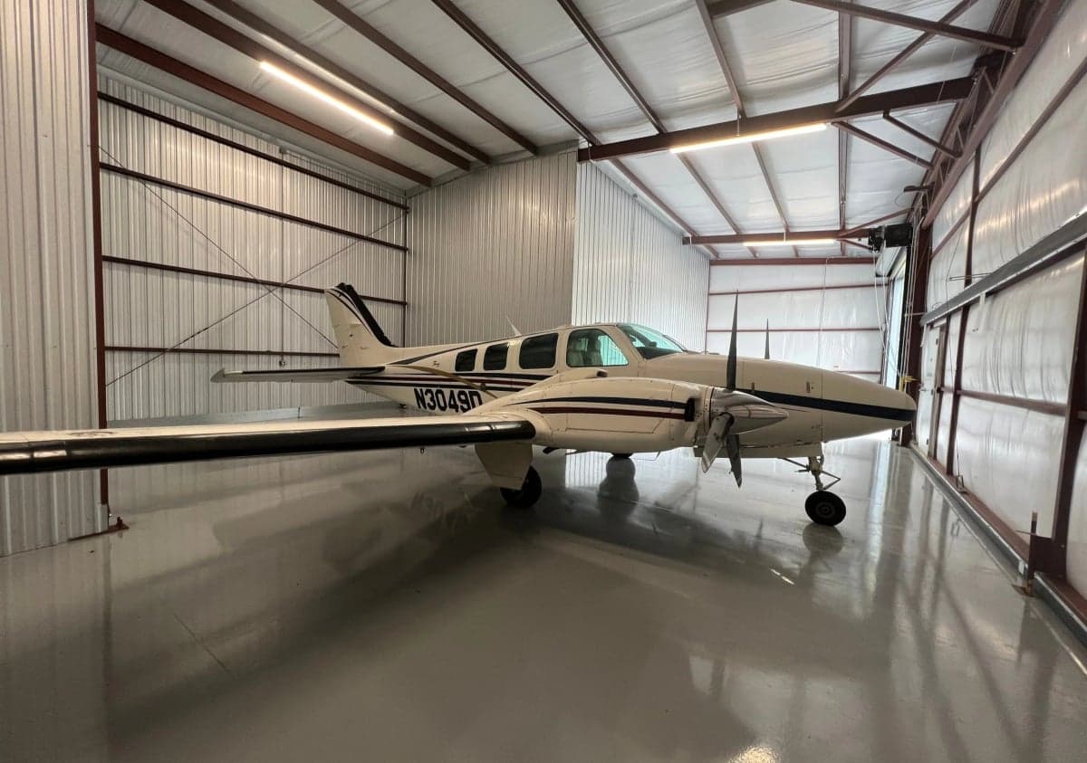 A Beechcraft Baron aircraft with registration N3049D is parked inside a hangar.