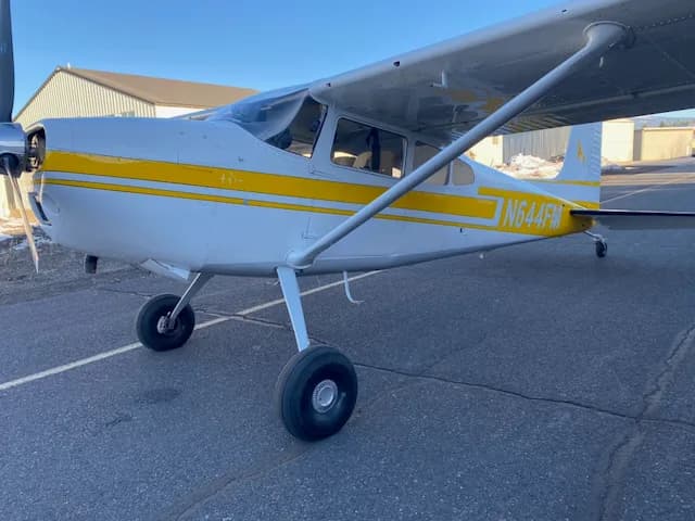 A front-left view of a white and yellow Cessna 172 aircraft with registration N644FM parked on a tarmac.