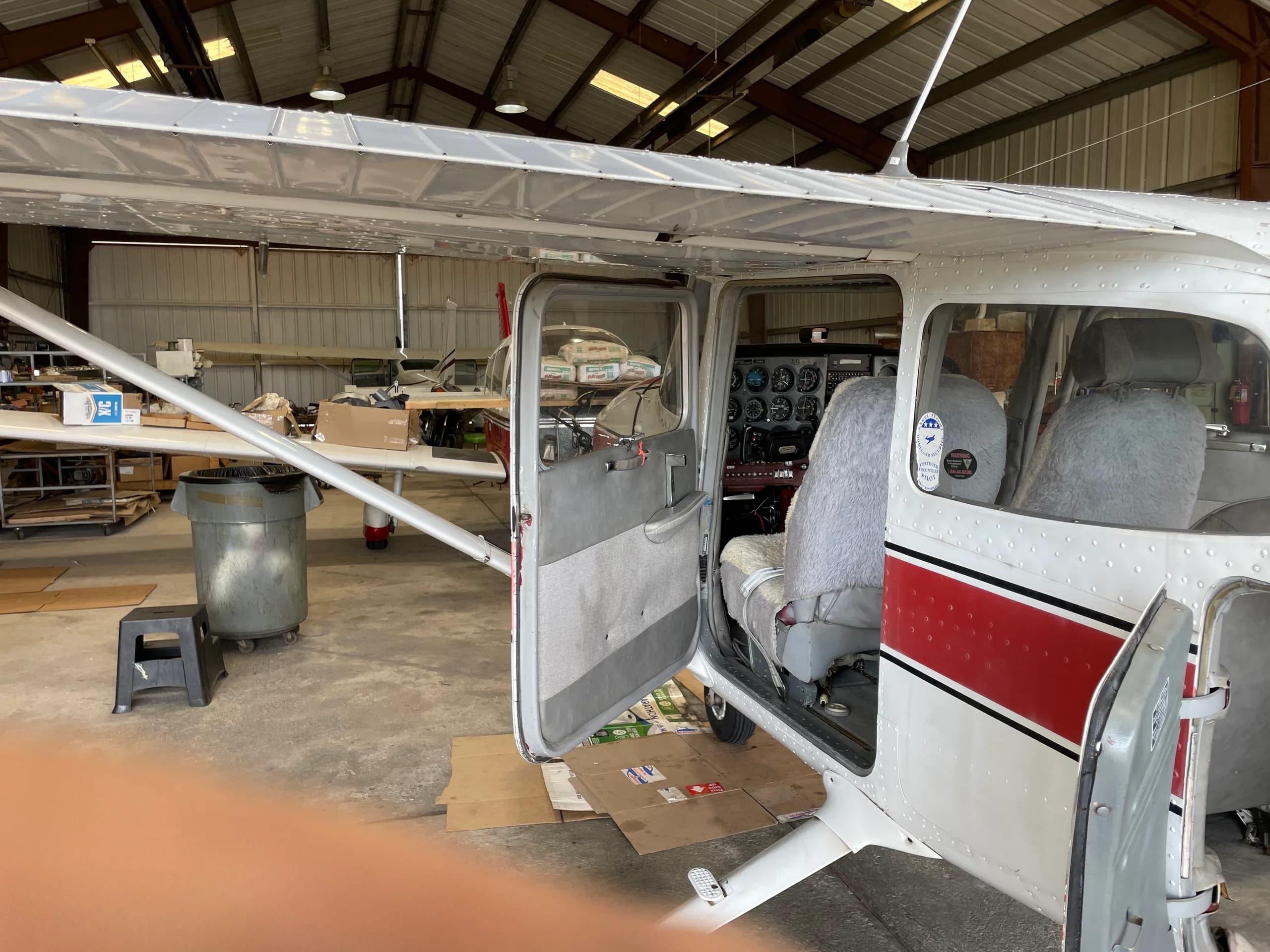 A side view of the Cessna 172 with both cabin doors open, revealing the interior seats and cockpit.