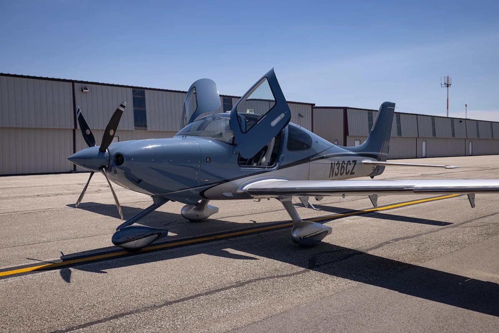A Cirrus SR22T aircraft with open doors is parked on the tarmac.
