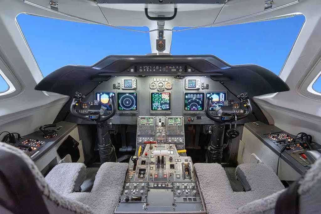 The modern cockpit of a private jet with multiple digital displays and control panels.