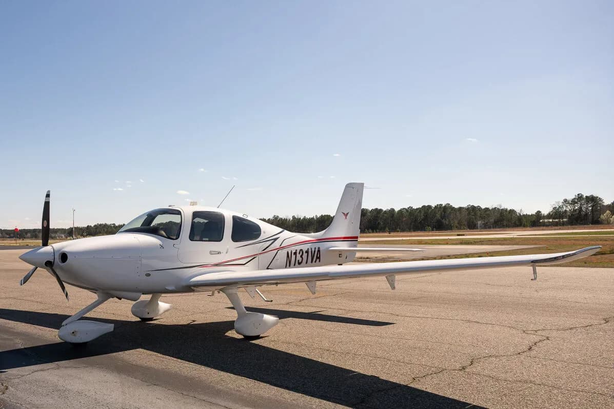 A white Cirrus SR22 aircraft with red and black accent stripes, tail number N131VA, parked on an airfield.