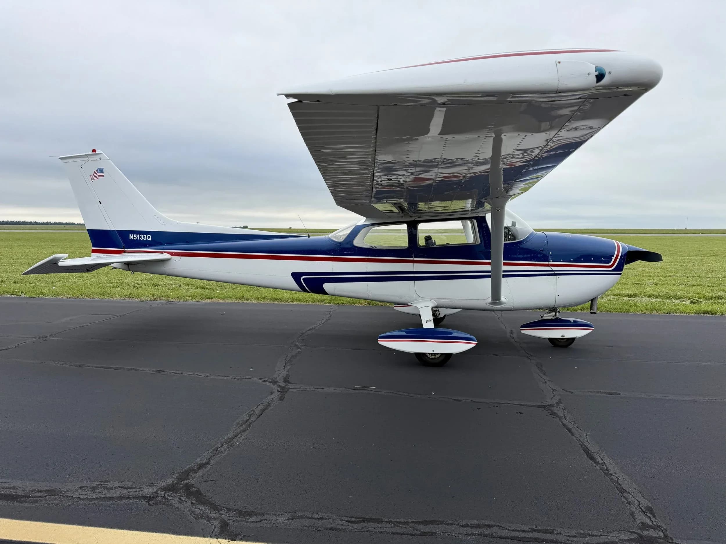 A side view of the blue and white Cessna 172 aircraft N5133Q parked on an asphalt surface.