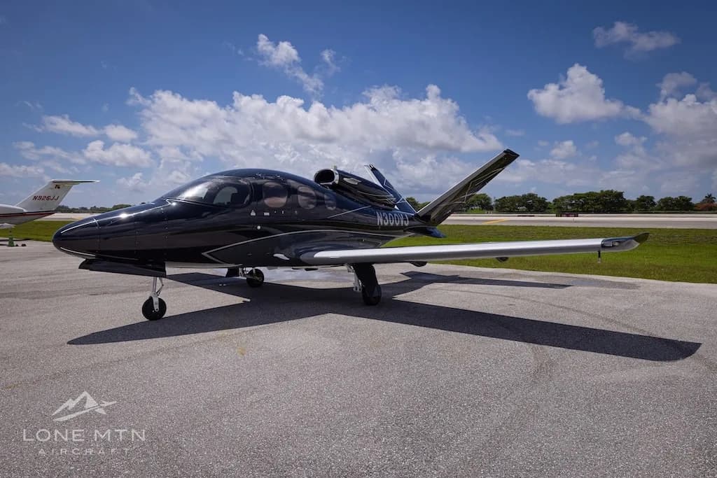 A black Cirrus Vision Jet (N300VJ) with silver accents parked on an airport tarmac, viewed from the front-left.