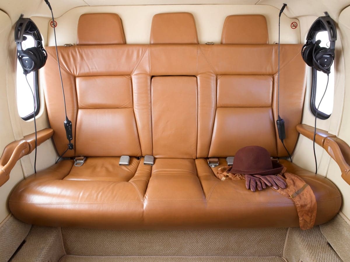 Rear cabin seats upholstered in brown leather with hat and gloves.