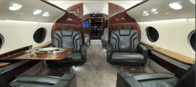 The aircraft's interior features leather seats and wood paneling.