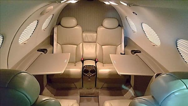 The interior of the aircraft cabin with leather seats and tables.