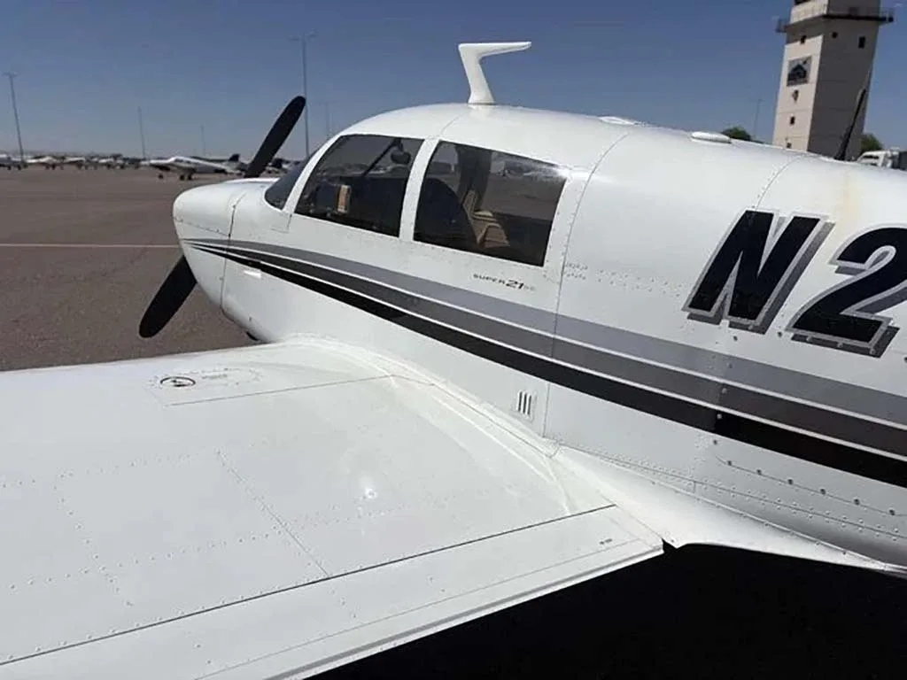 A close-up of the fuselage and wing of the white Mooney M20 aircraft N2634W, showing "SUPER 21" text.