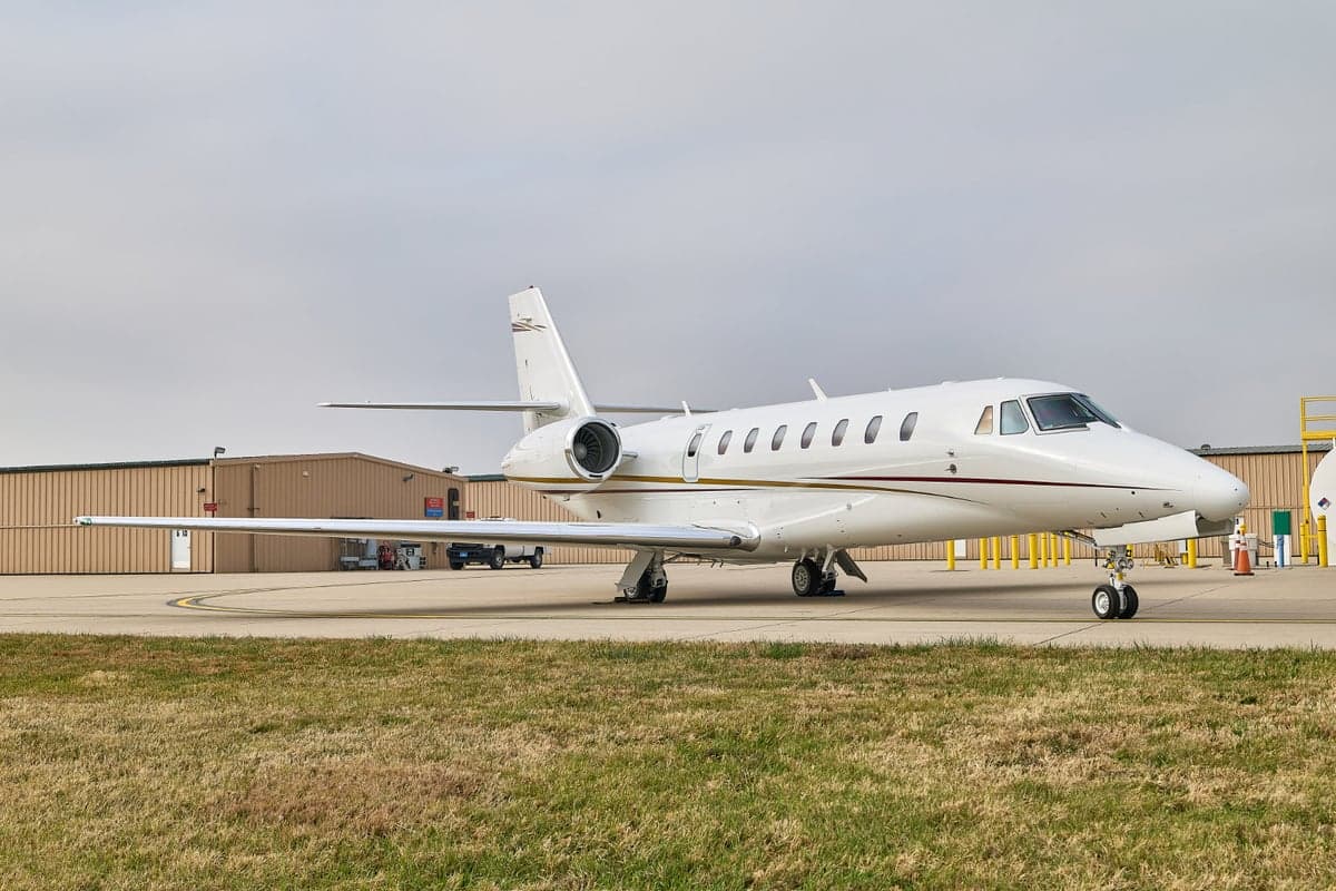 A white jet aircraft parked on the tarmac in front of a building.
