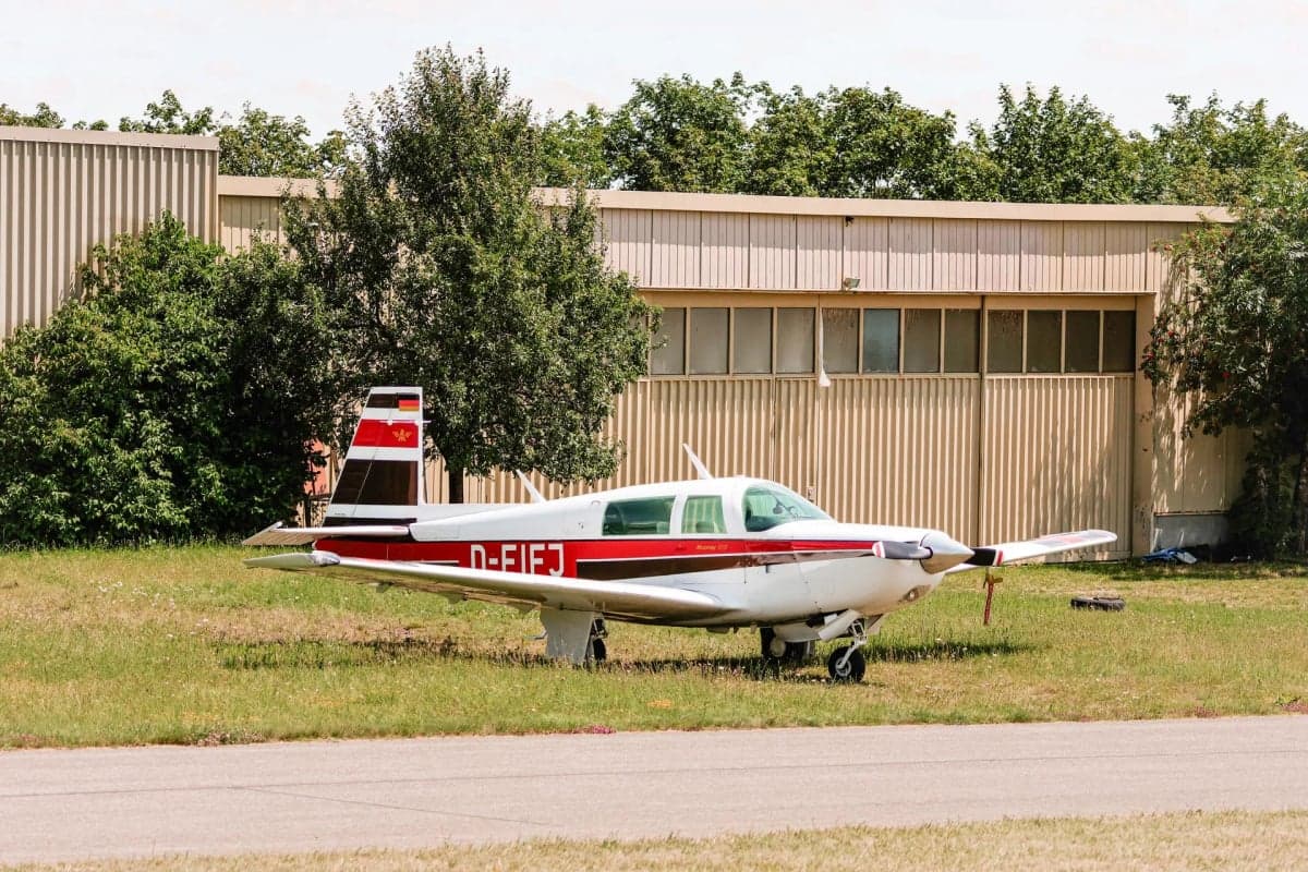 Mooney M20J aircraft D-EIFJ parked in front of a hangar.