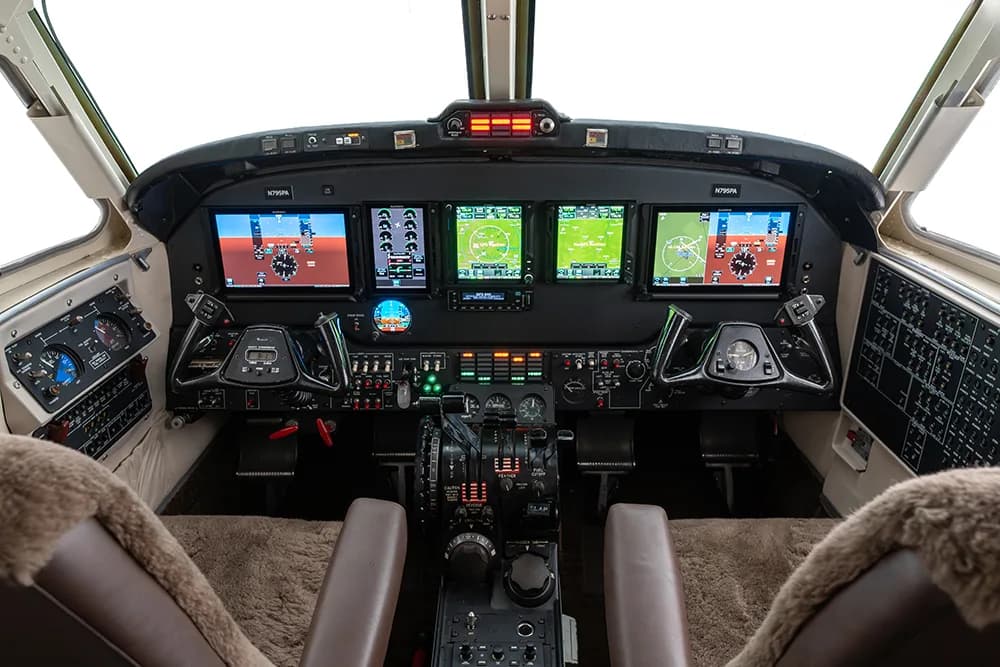 The cockpit of an aircraft, featuring multiple digital displays and traditional controls.