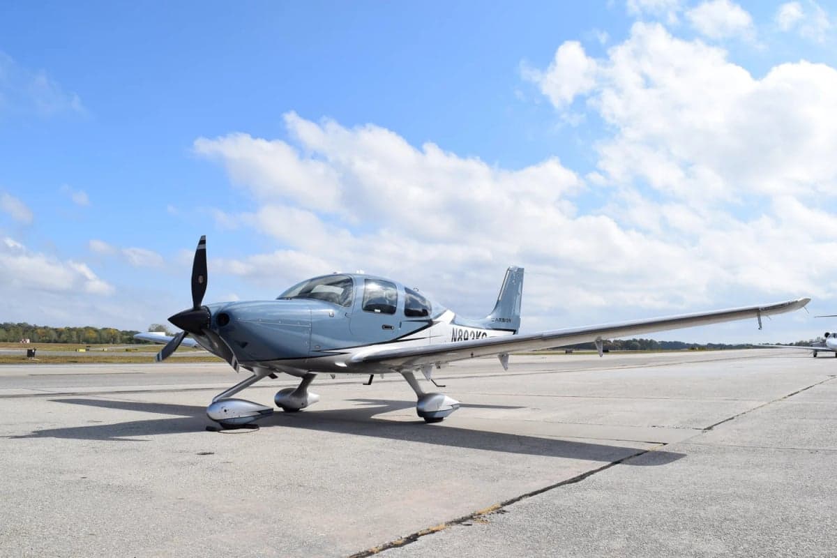 A Cirrus SR22T aircraft with a blue and silver paint scheme is parked on the tarmac.