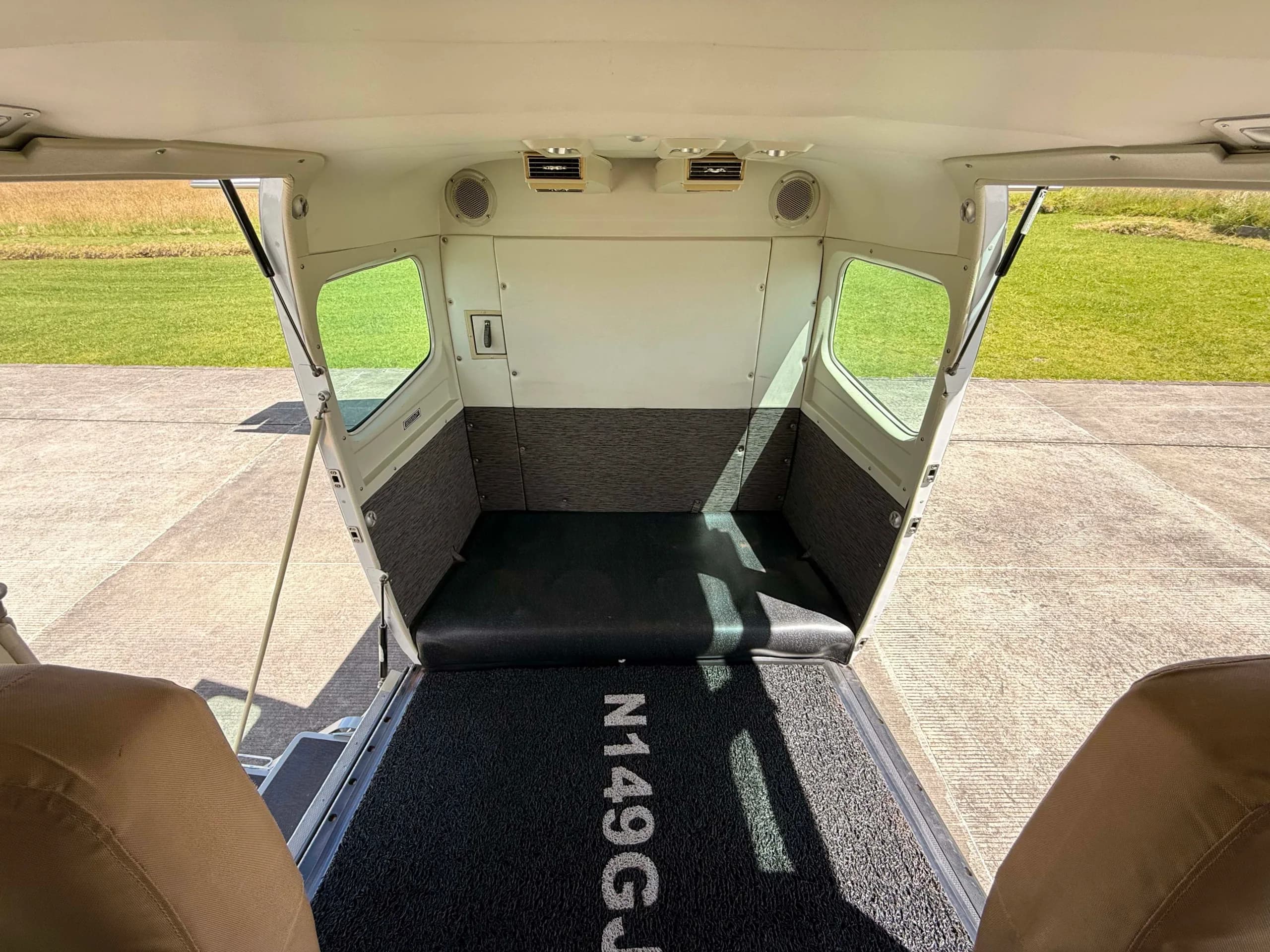 The rear cargo area of an aircraft with "N149GJ" on the floor mat, looking out the open door.
