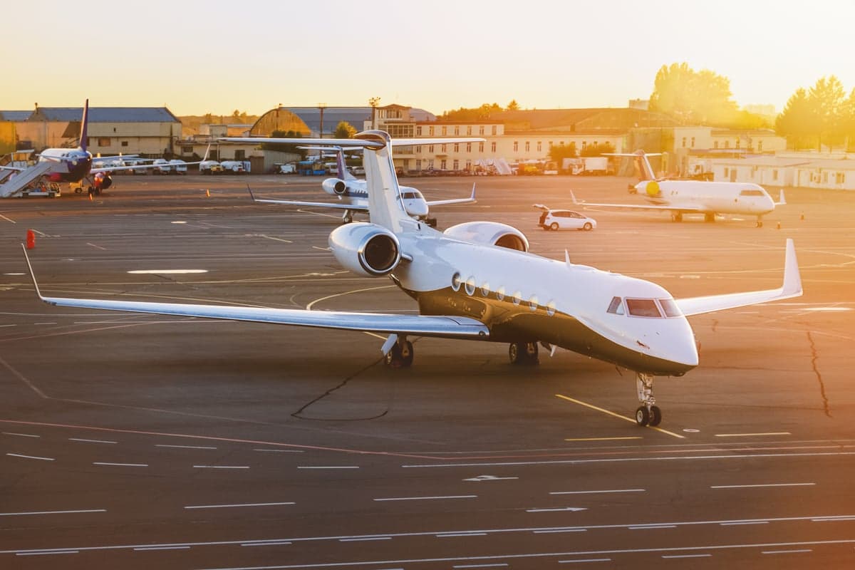 A white and gold Gulfstream jet parked on the tarmac at sunset.