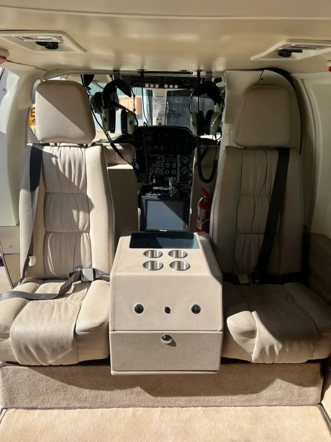 The helicopter's interior features tan leather seats and a center console with cup holders.