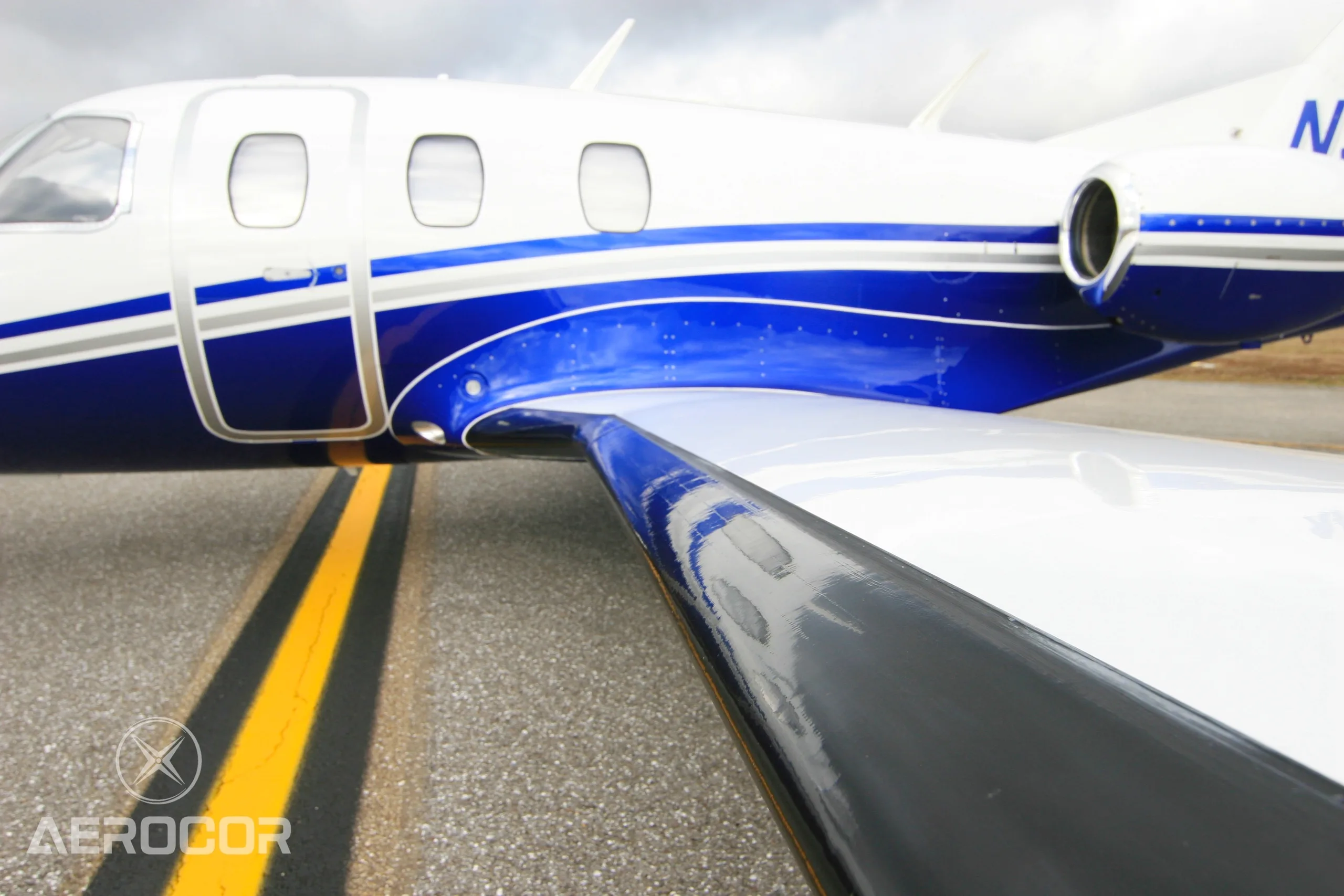 Close-up view of the white and blue fuselage and wing of the Eclipse 500 jet.