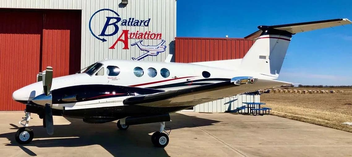 Beechcraft King Air on the tarmac in front of a hangar.