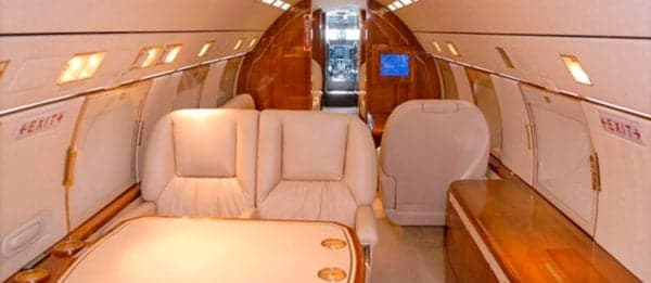 Interior of the aircraft with cream-colored seats and wood accents.