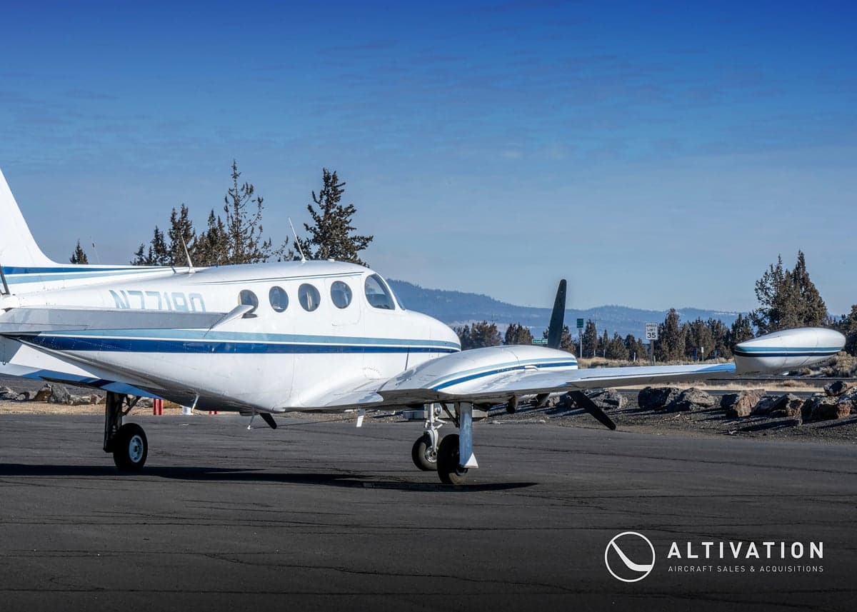 A white and blue twin-engine aircraft, registration N7719Q, sits on the tarmac.
