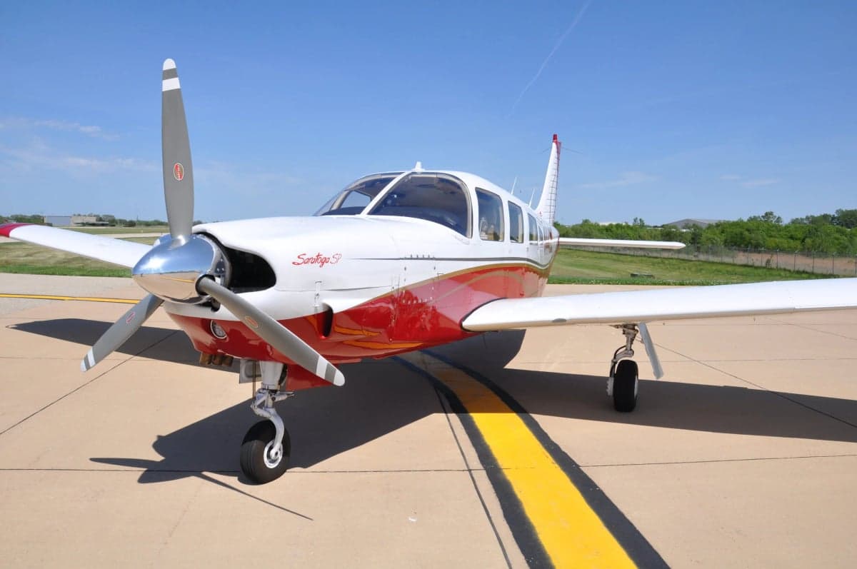 Close up of the front of a Piper Saratoga with red and white paint scheme.