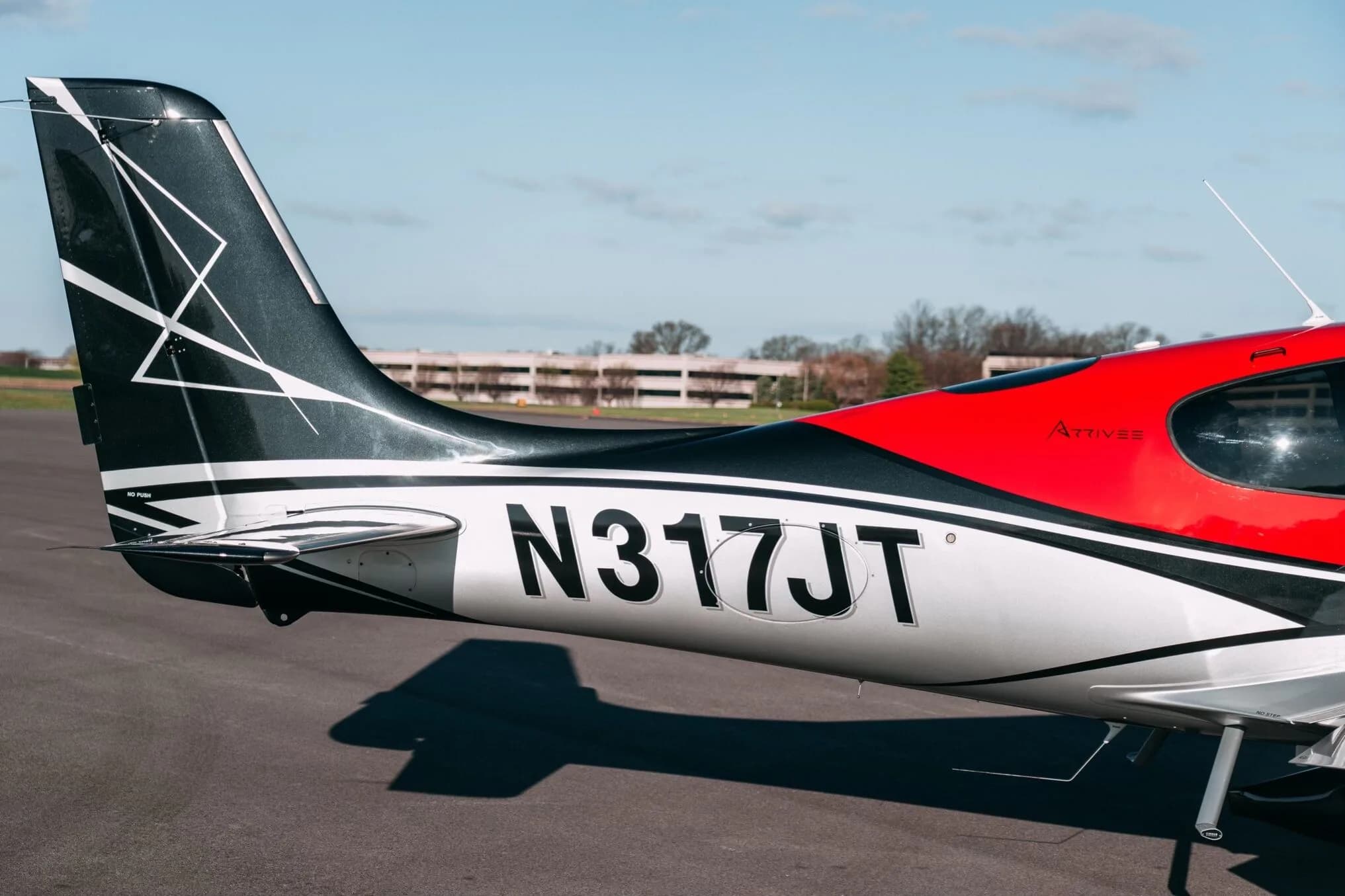 A close-up of the tail section of the Cirrus SR22T aircraft, showing the N317JT registration and black, silver, and red paint scheme.