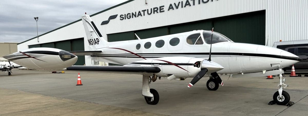 Front side view of the Cessna 340A aircraft with registration N51AP parked in front of a Signature Aviation hangar.
