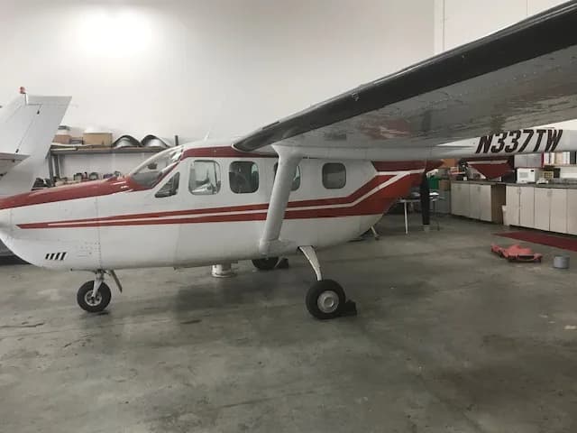 A white and red Cessna 337 Skymaster aircraft with registration N337TW parked in a hangar.