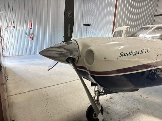 Close-up of the nose and propeller of the Piper Saratoga II TC aircraft in a hangar.