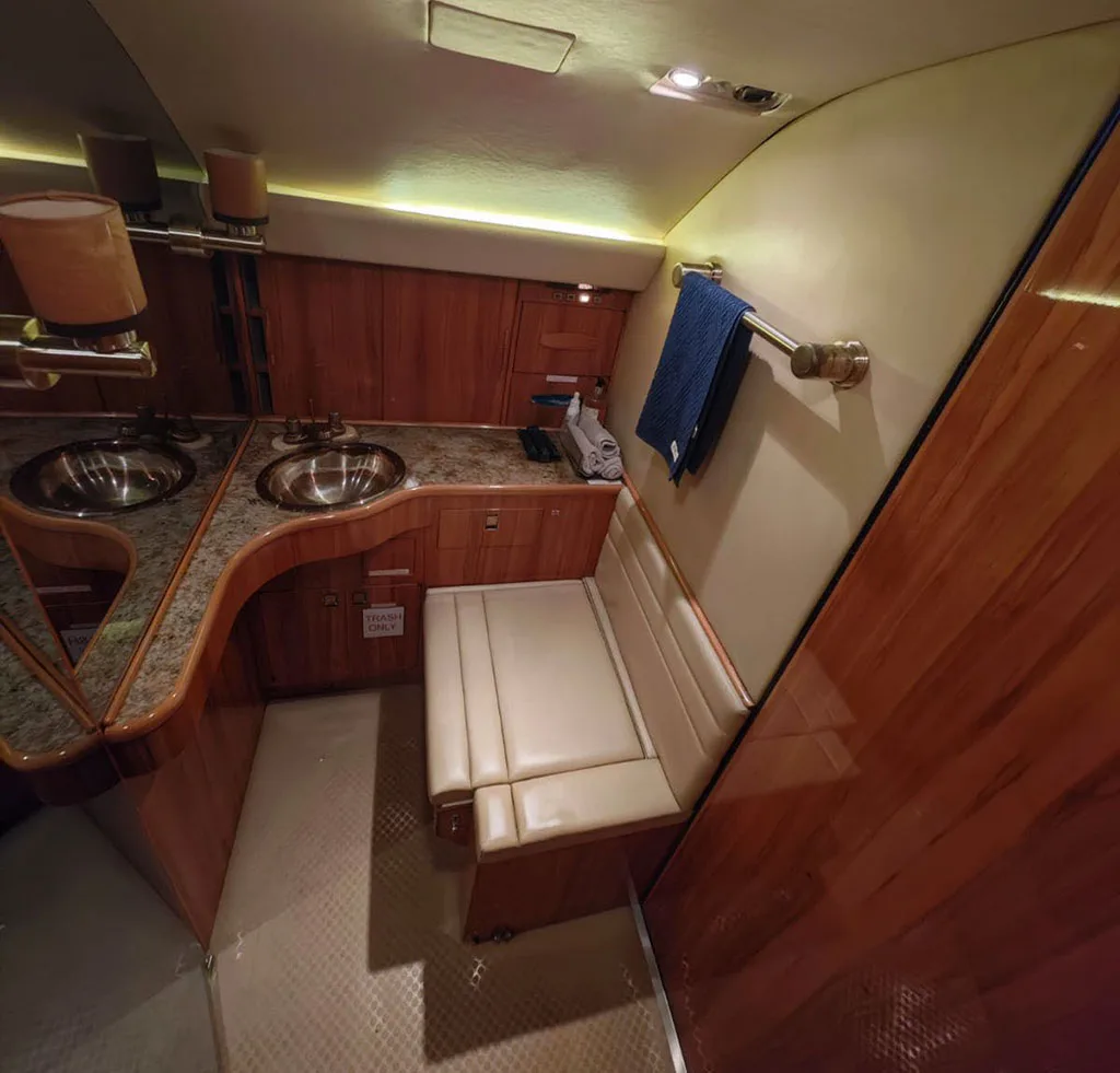 The aircraft's galley area with two sinks, a counter, wood cabinetry, and a small bench seat.