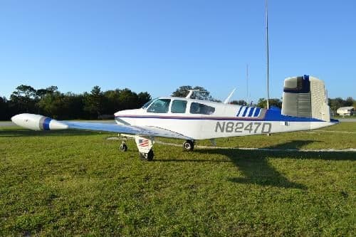 A Beechcraft Bonanza is parked on the grass with the tail number N8247D.