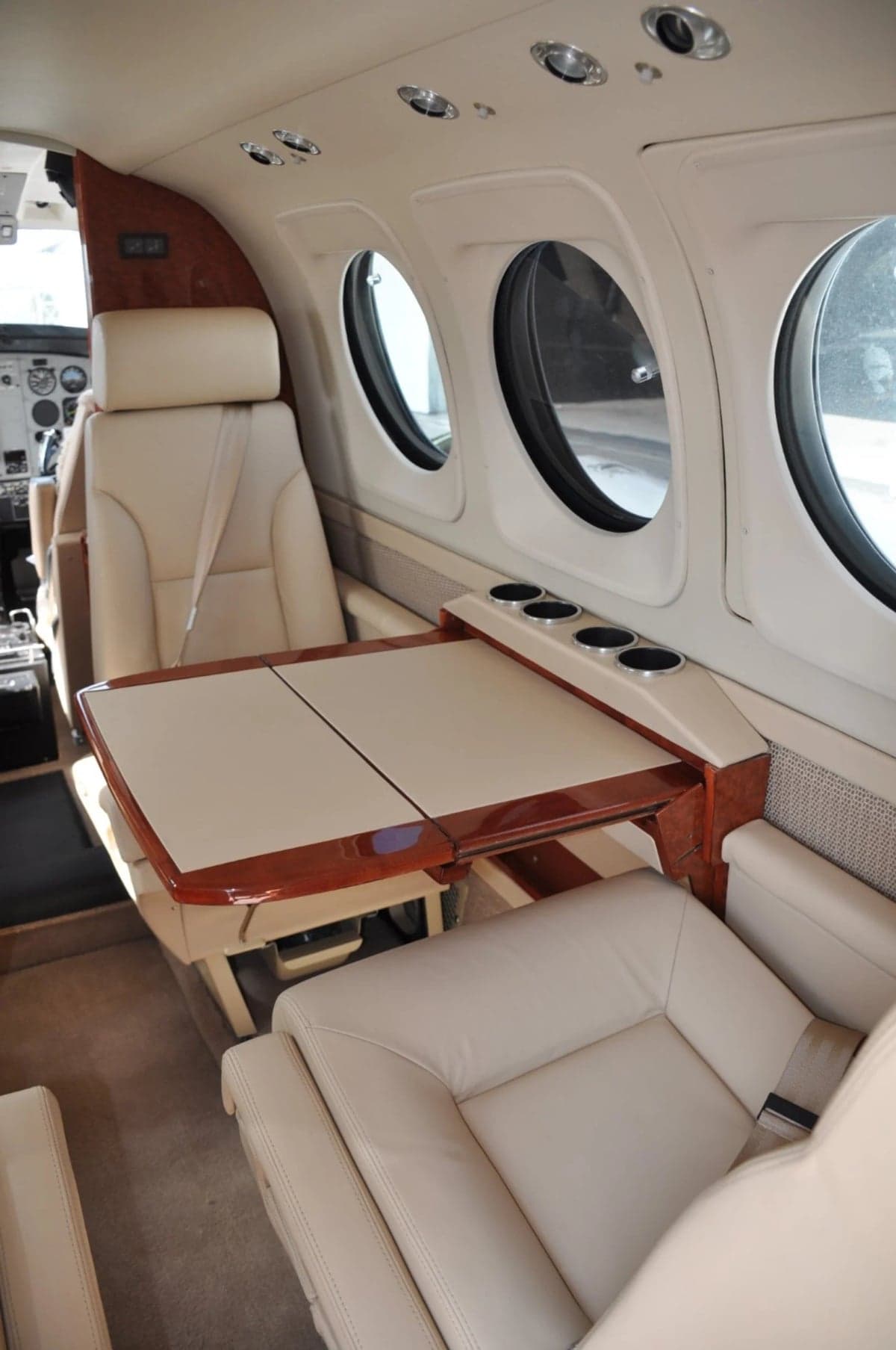 Interior view of the aircraft cabin with a table and cream-colored leather seats.