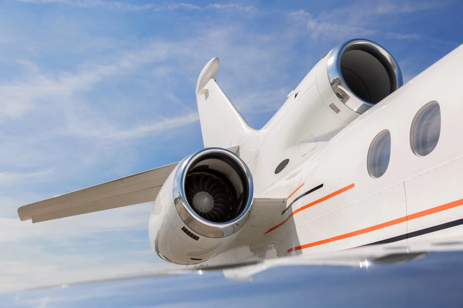 Close-up of the tail and engines of a white aircraft against a blue sky.