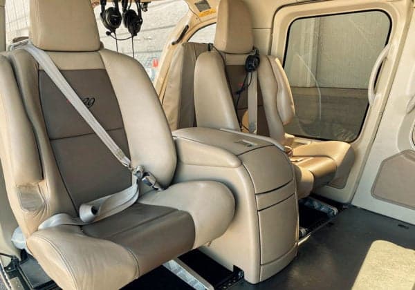 Two tan leather seats with headsets in the helicopter's cabin.