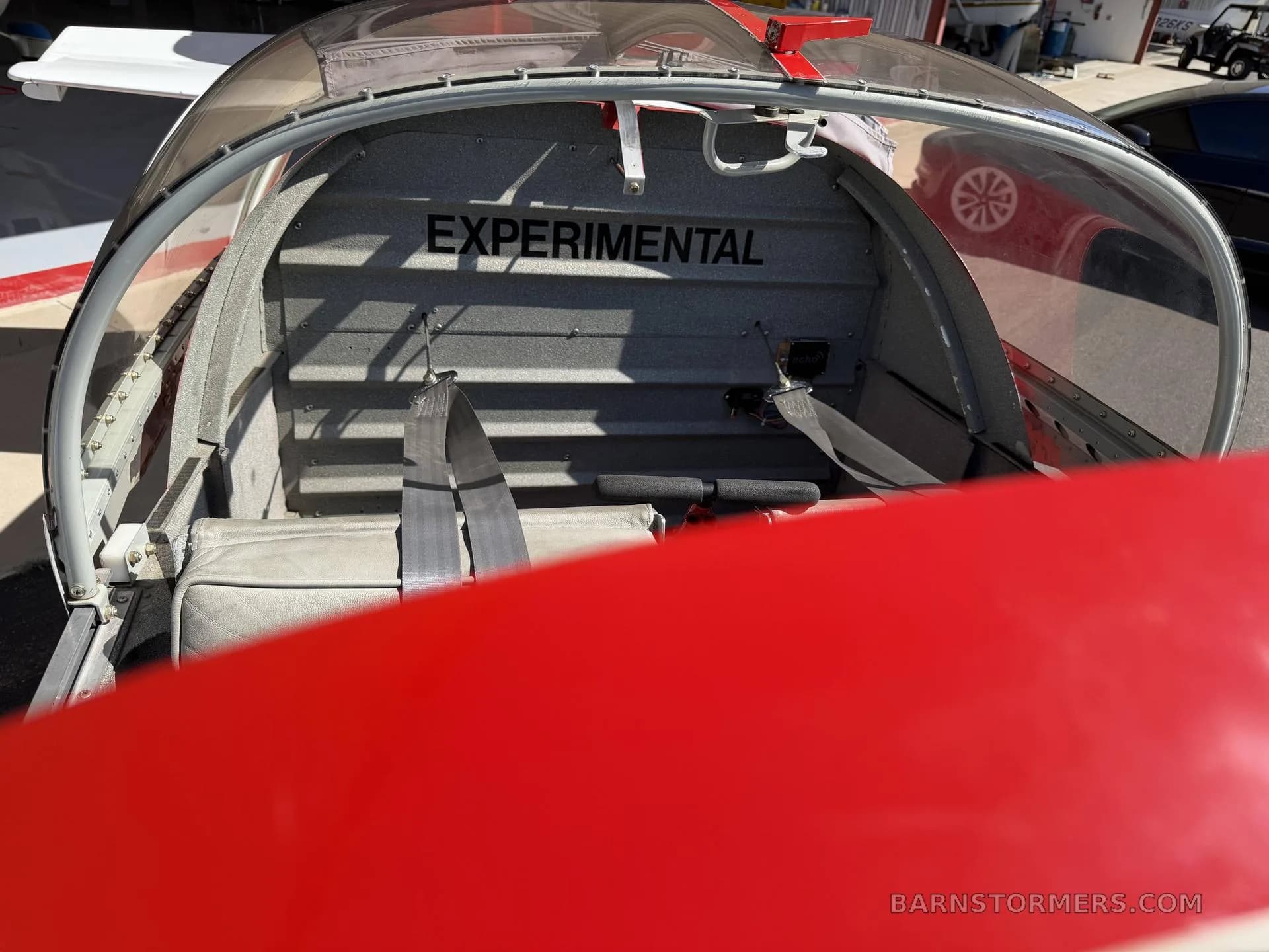 The interior of the Vans RV-7A aircraft, showing the rear baggage area with "EXPERIMENTAL" written on the bulkhead and seatbelts.