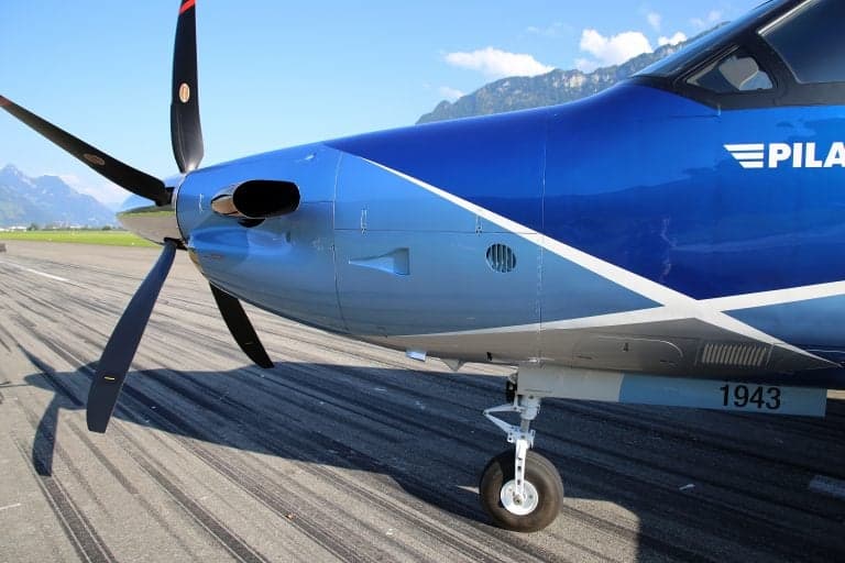 Close-up of the front of a Pilatus PC-12 NGX, showing the propeller and landing gear.