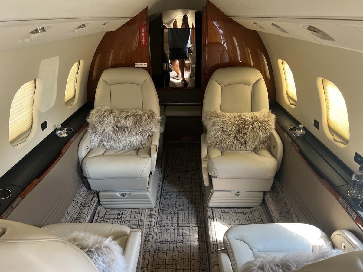 Interior view of the aircraft cabin with leather seats and decorative pillows.