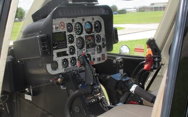 A close-up view of a helicopter cockpit with various instruments and flight controls.