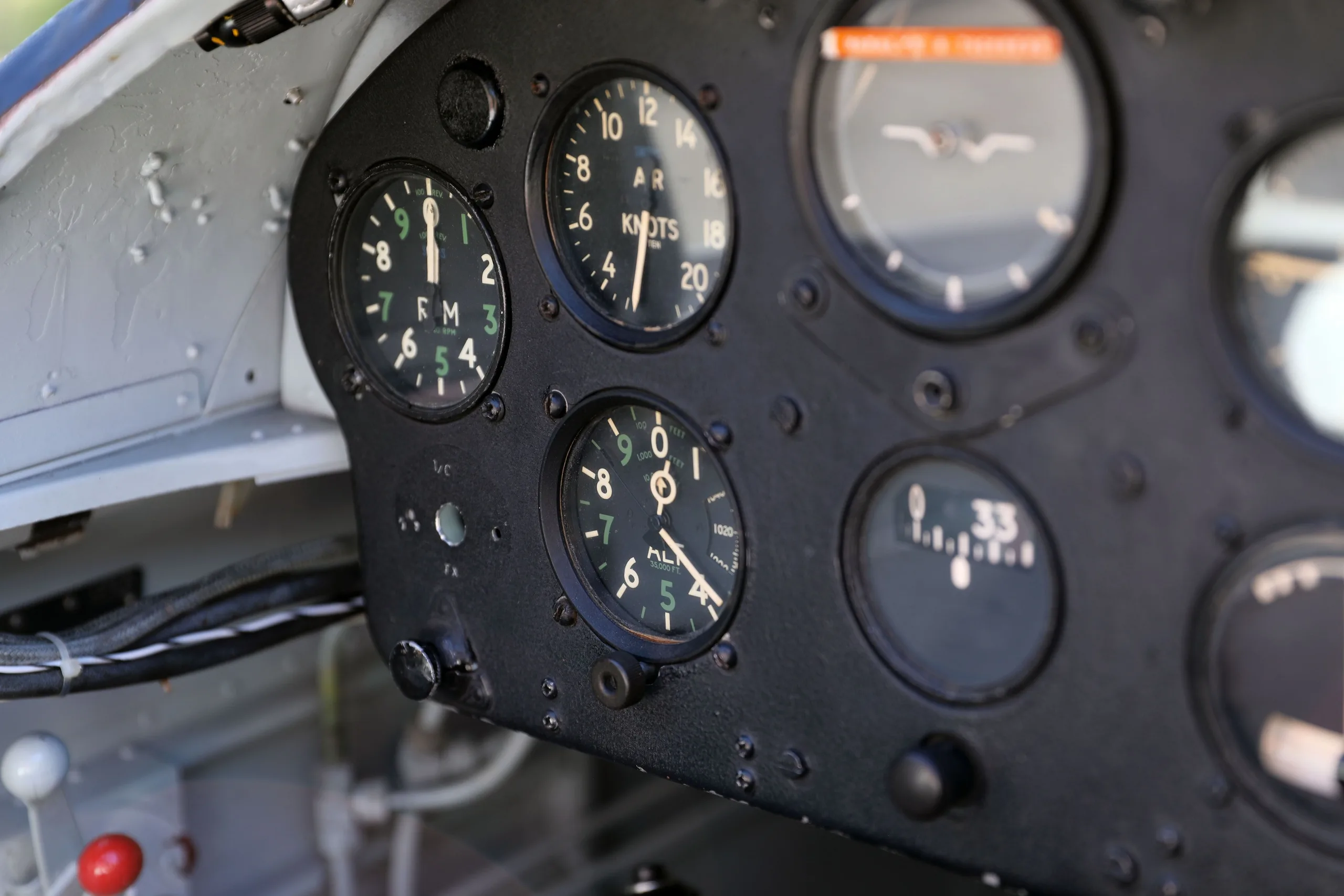A close-up, angled view of the left side of a vintage aircraft instrument panel with several round gauges.