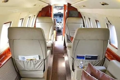 A view of the aircraft's interior with leather seats and a view of the cockpit.
