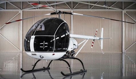 A white and blue helicopter is parked in a hangar.