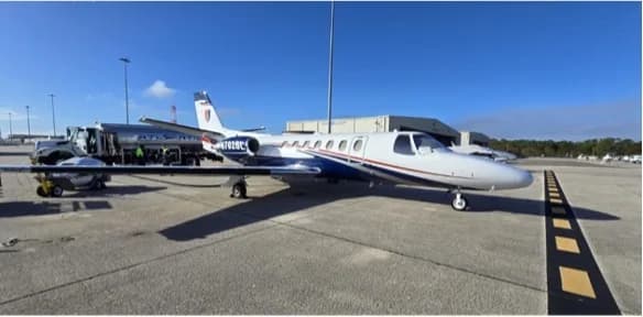 A Cessna Citation business jet, registration N702SL, being refueled on an airport tarmac under a clear blue sky.