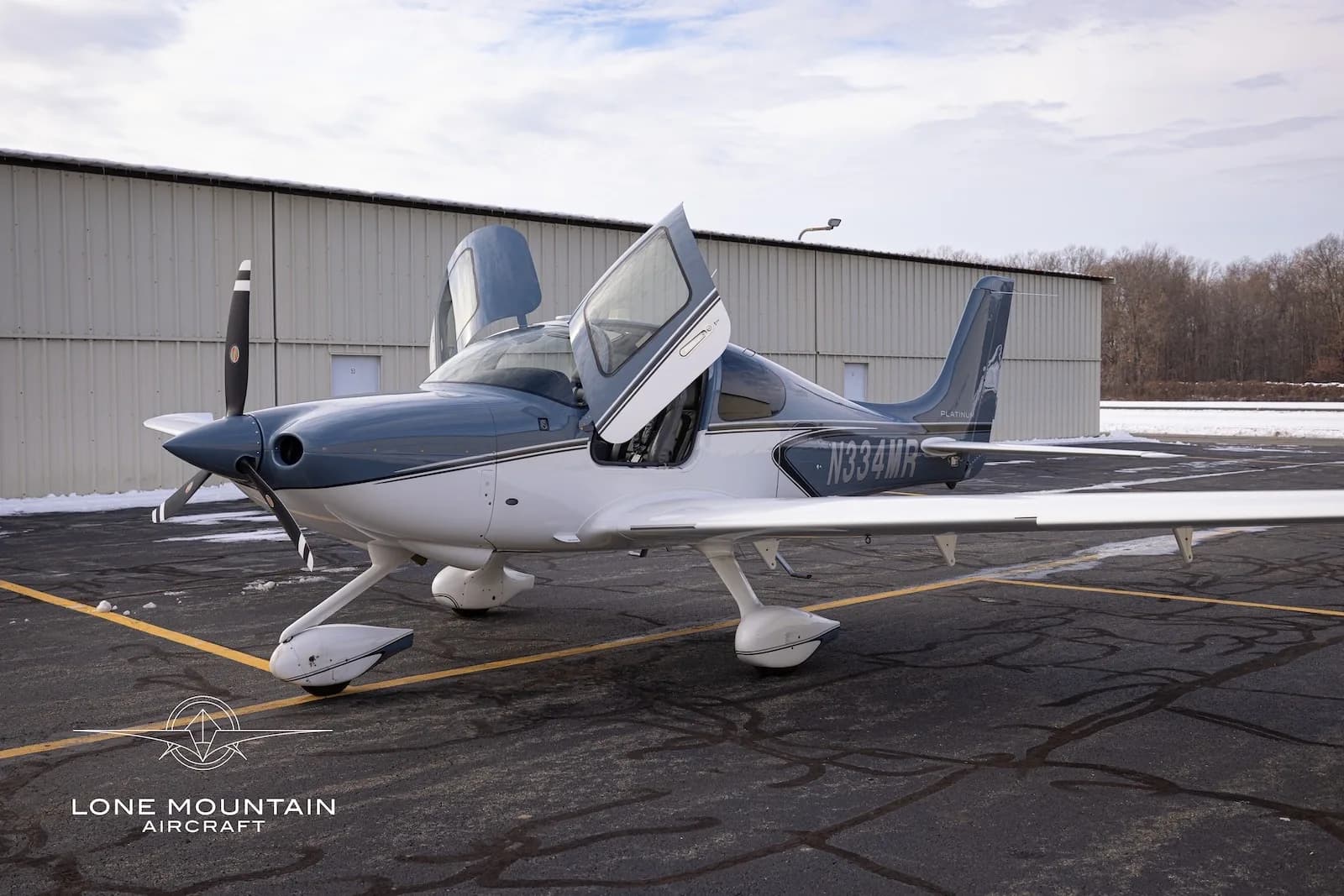 A front-side view of the Cirrus SR20 aircraft, N334MR, with its gull-wing doors open.