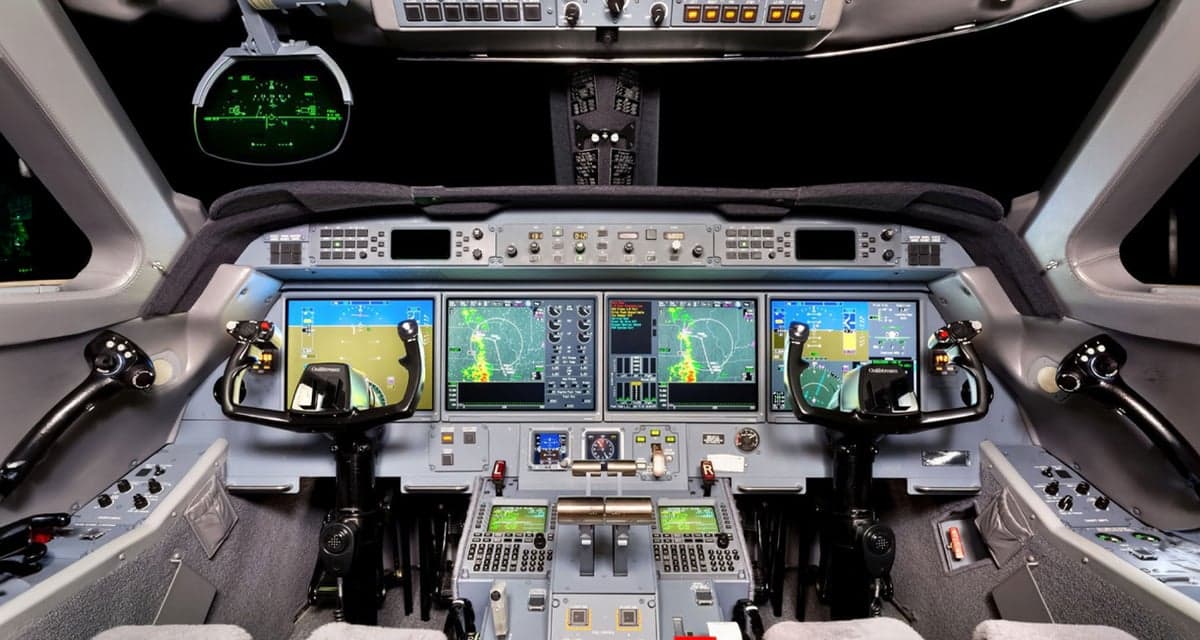 The modern cockpit of a business jet features multiple large digital displays and a complex control panel.