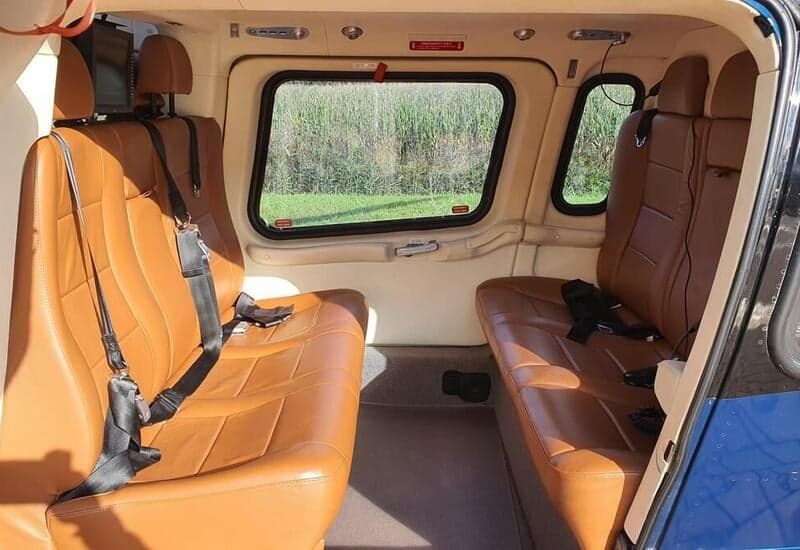 The interior of the helicopter features tan leather seats and a view out the window.