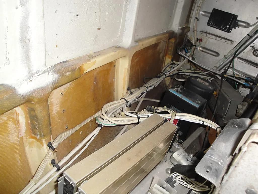 Close-up view of an aircraft's internal structure with bundles of white wires, electronic components, and exposed composite panels.