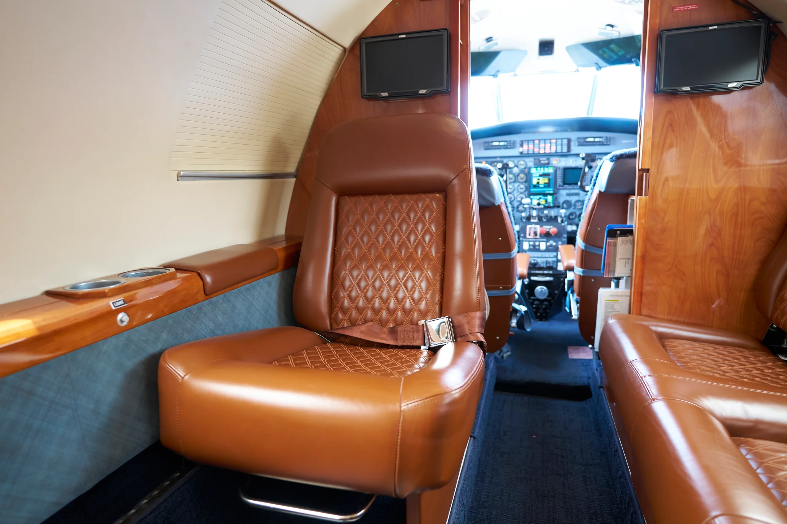 The aircraft's cabin interior with a single brown quilted leather seat in the foreground and the cockpit visible ahead.