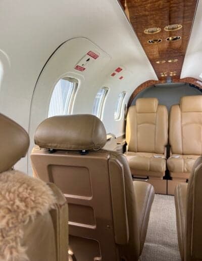 View of the aircraft cabin with tan leather seats and wood trim.